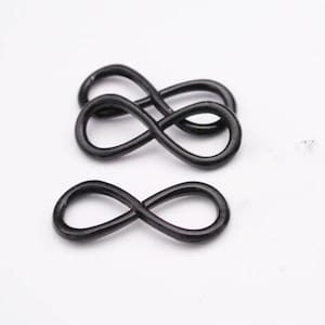 May include: Three black metal infinity symbol charms. The charms are approximately 2.5 cm in diameter.