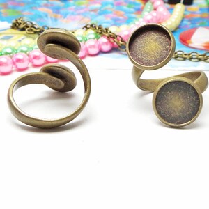 Op de afbeelding: Twee verstelbare ringen van brons met ronde, platte bezettingen. De ringen zijn open en kunnen worden aangepast aan verschillende vingermaten.