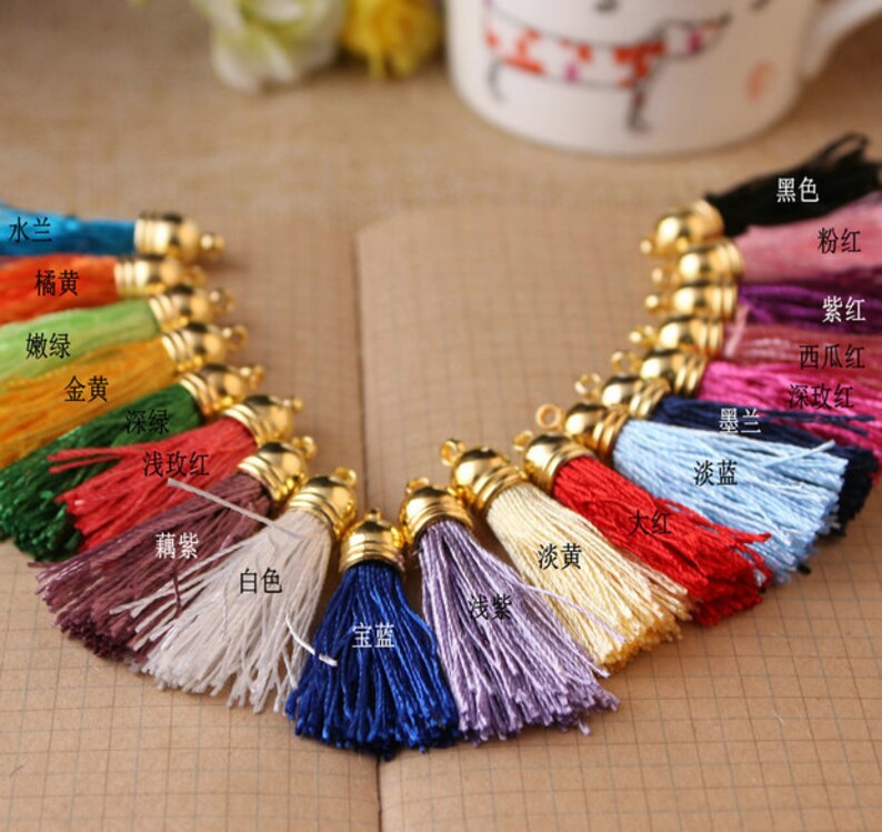 May include: Assortment of 16 colorful tassel trims with gold metal caps. The tassels are arranged in a semi-circle and labeled with their corresponding colors in Chinese characters.
