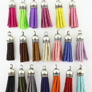 Puede incluir: Una colecci&oacute;n de colgantes de borlas coloridas con tapas y lazos de metal plateado. Las borlas vienen en varios colores, incluyendo rosa, verde, morado, burdeos, amarillo, marr&oacute;n, beige, rosa, azul y lavanda. Colores adicionales incluyen negro, verde oliva, gris, azul marino, naranja, rojo y turquesa.