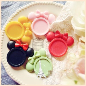 Könnte beinhalten: Sortiment an bunten Harz-Cabochons mit Mickey-Maus-Ohren-Design. Jeder Cabochon hat eine andere Farbe und eine runde, flache Oberfläche. Die Cabochons sind perfekt für Bastelprojekte wie Schmuckherstellung, Scrapbooking und Harz-Kunst.