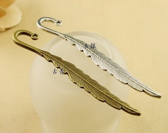 May include: Two feather-shaped bookmarks, one silver and one bronze, with a hook at the top. The bookmarks have Chinese characters on them.