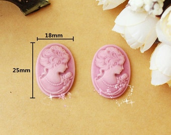 May include: Two pink cameo-style resin cabochons, each featuring a woman's profile with a floral design. The cabochons are 18mm wide and 25mm tall.