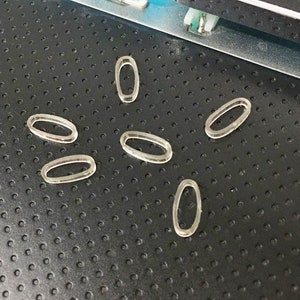 以下が含まれることがあります： キーボード用の透明なプラスチック製のキーキャップが7つ。キーキャップは楕円形で、滑らかで光沢のある仕上げになっています。
