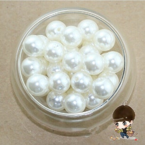 May include: A bowl filled with white pearl beads. The beads are smooth and round, and they are perfect for crafting or jewelry making.