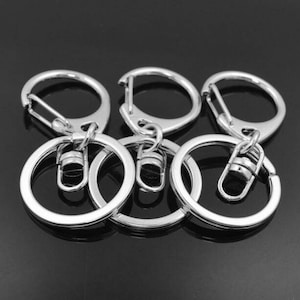 May include: Five silver key rings with a swivel clasp. The key rings are linked together.