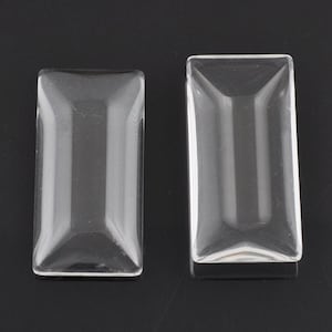 May include: Two clear glass rectangular shapes with bevelled edges. The shapes are slightly different sizes.