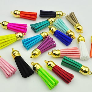 Puede incluir: Una colecci&oacute;n de borlas coloridas con tapas doradas. Las borlas est&aacute;n disponibles en varios tonos, incluyendo rosa, negro, verde, azul y naranja. Estas borlas decorativas son adecuadas para la fabricaci&oacute;n de joyas, manualidades o para a&ntilde;adir estilo a los accesorios.