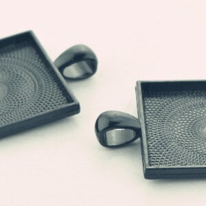 May include: Two black metal square pendant trays with a textured surface and a loop at the top for hanging.