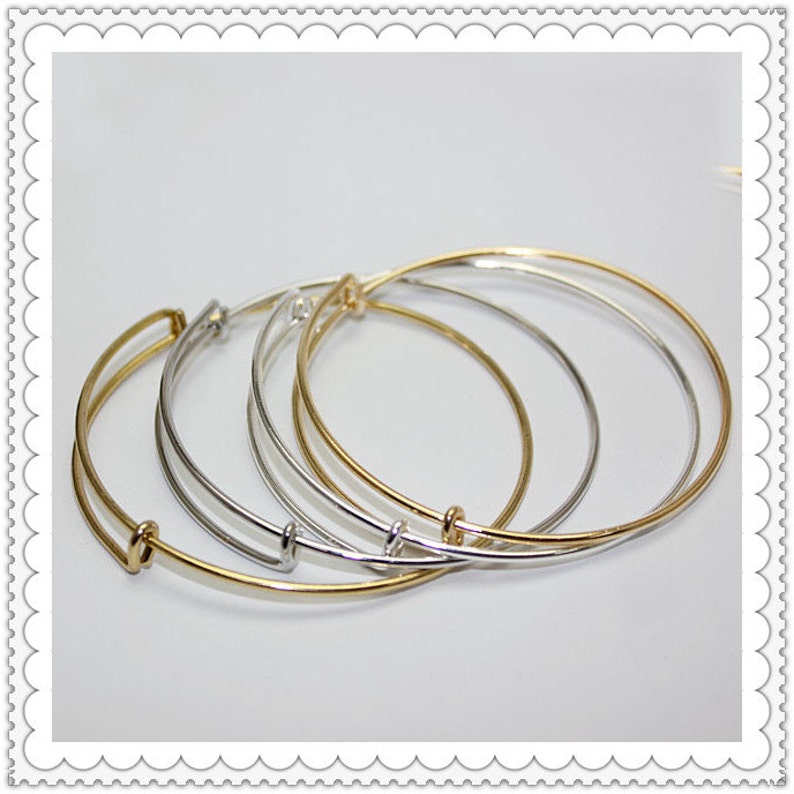 May include: Three expandable bangle bracelets in gold and silver tones. The bracelets are stacked on top of each other.