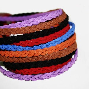 Può includere: Un mucchio di cordini in pelle scamosciata intrecciati in vari colori, tra cui viola, marrone, nero, rosso, blu, arancione e marrone.
