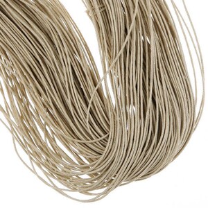May include: A close-up of a bundle of natural beige twine or cord. The twine is tightly wound together, creating a thick, textured rope.