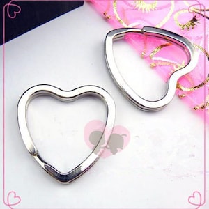 May include: Two silver heart-shaped keychains. The keychains are made of metal and have a smooth finish.