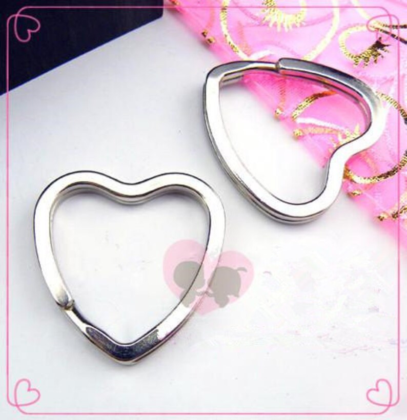 May include: Two silver heart-shaped keychains. The keychains are made of metal and have a smooth finish.