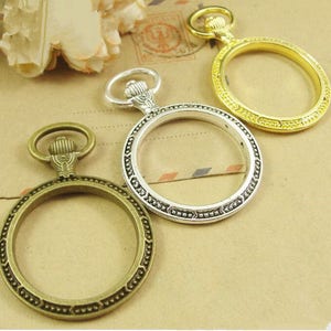 Pode incluir: Três bezéis de relógio de bolso de estilo antigo em prata e ouro com detalhes ornamentados. Os bezéis estão vazios e prontos para serem preenchidos com um mostrador de relógio.