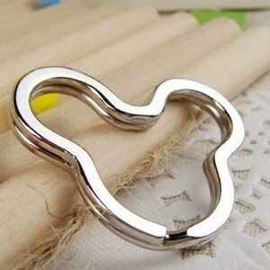 May include: Silver-toned metal key chain with a unique, wavy, heart-shaped design.