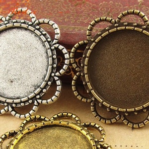 May include: Three silver, bronze, and gold metal round pendant trays with a decorative filigree design. The trays are blank and ready to be filled with resin, photos, or other embellishments.