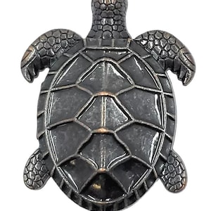 May include: A detailed, metallic sea turtle figurine. The turtle is dark gray with a textured shell and flippers. The design features a geometric pattern on the shell and a slightly raised head.