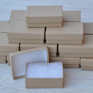 May include: A stack of brown cardboard boxes, some with white interior lining, arranged in a pyramid shape. The boxes are all the same size and are likely used for packaging small items.