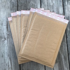 May include: A stack of brown padded envelopes with a red and white adhesive strip.