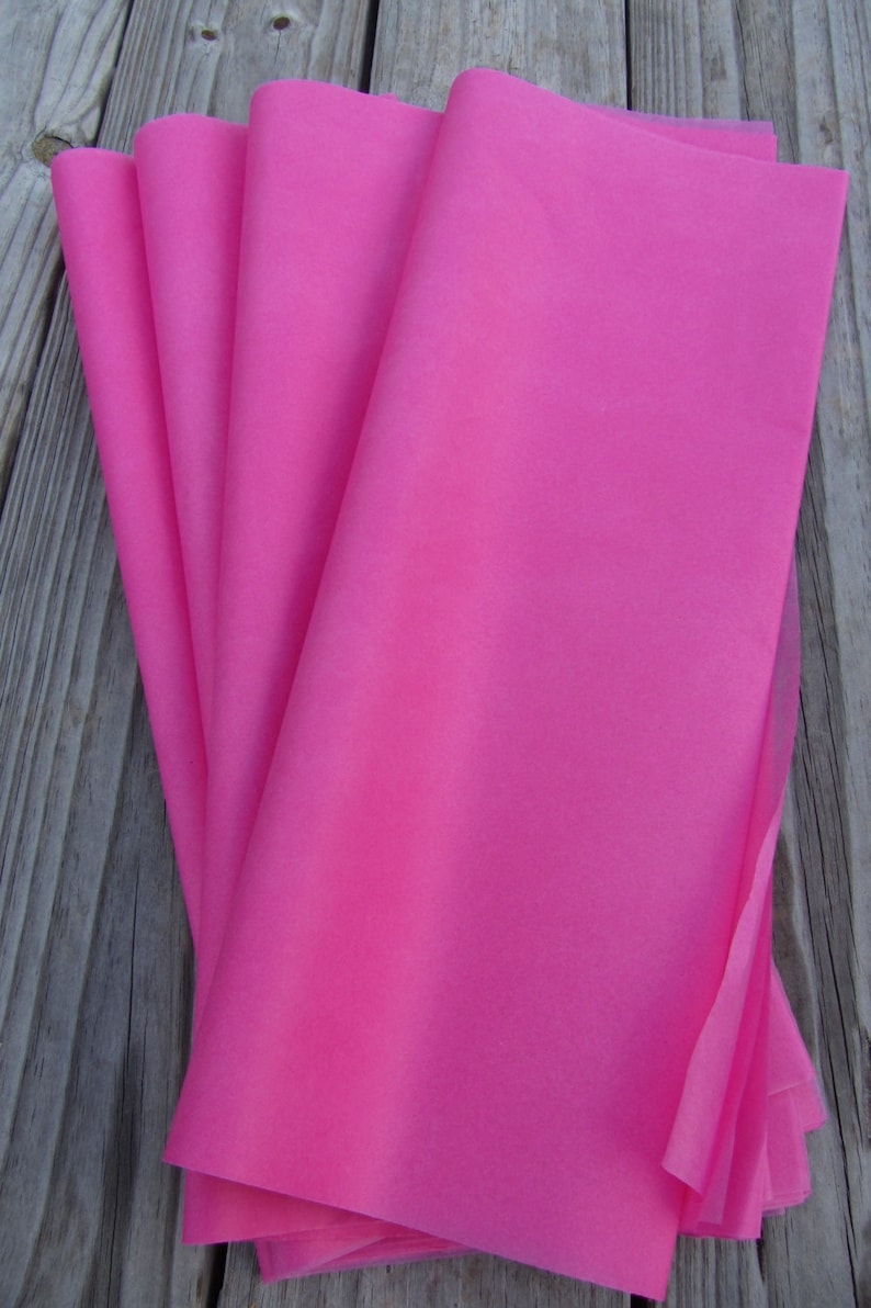May include: A stack of pink tissue paper. The tissue paper is folded in half and the edges are visible.