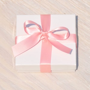 May include: A white gift box with a pink satin ribbon tied in a bow.