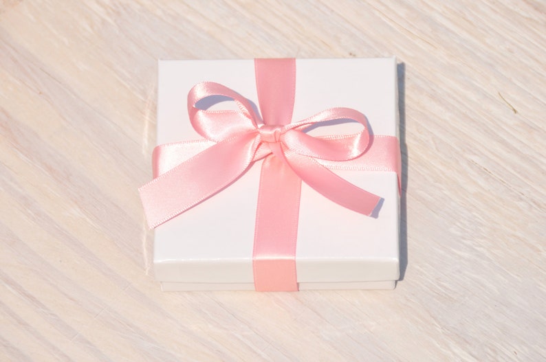 May include: A white gift box with a pink satin ribbon tied in a bow.