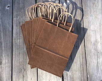 May include: A stack of brown paper gift bags with twisted paper handles.