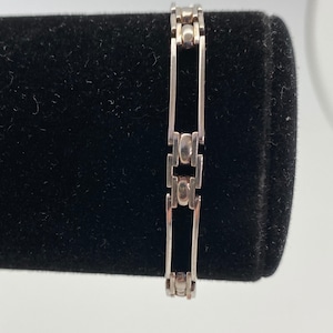 May include: A silver bracelet with a chain link design. The bracelet has a polished finish and is made of metal.