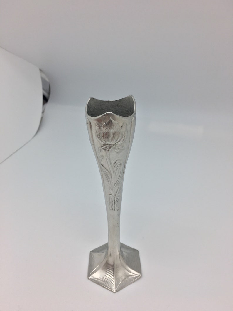 Pu&ograve; includere: Un vaso portafiori argentato con base esagonale e stelo sottile. Il vaso presenta un motivo floreale e una parte superiore svasata. Il vaso &egrave; in metallo ed &egrave; progettato per un singolo fiore.
