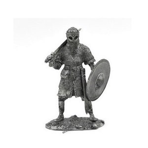 May include: A pewter figurine of a Viking warrior wearing chainmail armour, a helmet with a nose guard, and holding a sword and shield.