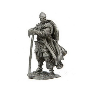 Könnte beinhalten: Eine Zinnfigur eines Wikingerkriegers, der eine Axt und einen Schild hält. Der Krieger trägt einen Helm, Kettenhemd und einen Umhang. Die Figur ist in Grautönen und Silber bemalt.