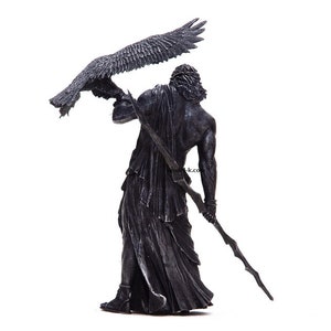 May include: A black and silver statue of a figure holding a staff and a bird with outstretched wings.