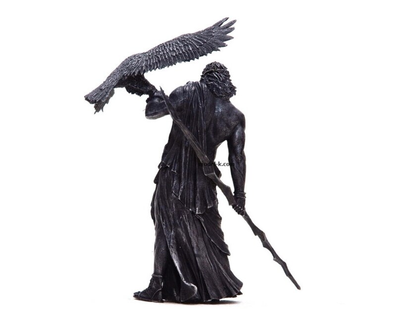 May include: A black and silver statue of a figure holding a staff and a bird with outstretched wings.