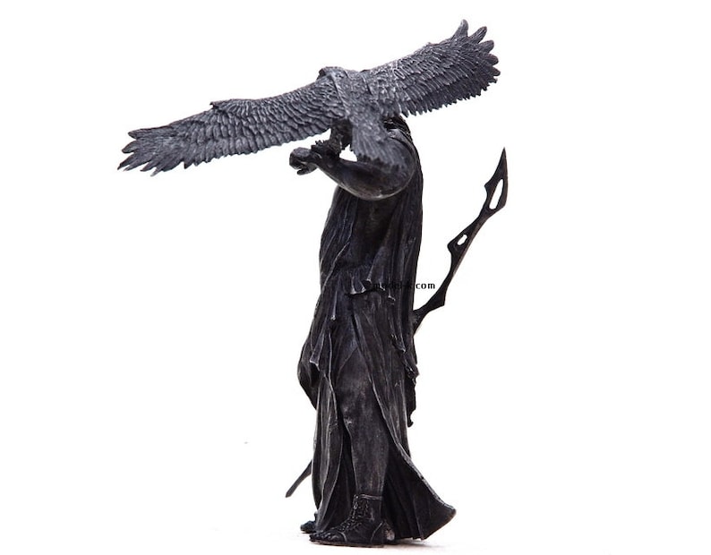 May include: A black and silver statue of a figure holding a bird with outstretched wings. The figure is wearing a long robe and holding a spear.