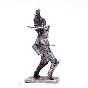 K&ouml;nnte beinhalten: Eine silberne Metallfigur eines Kriegers, der ein Schwert und einen Schild h&auml;lt. Der Krieger tr&auml;gt eine R&uuml;stung und einen Helm mit einer Feder. Die Figur steht auf einem kleinen Sockel.