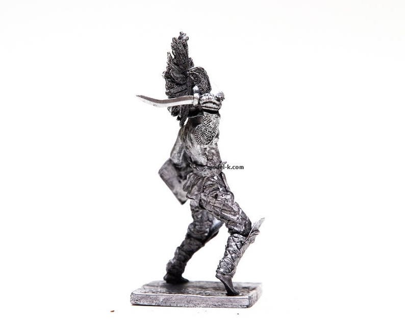 K&ouml;nnte beinhalten: Eine silberne Metallfigur eines Kriegers, der ein Schwert und einen Schild h&auml;lt. Der Krieger tr&auml;gt eine R&uuml;stung und einen Helm mit einer Feder. Die Figur steht auf einem kleinen Sockel.