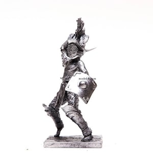 K&ouml;nnte beinhalten: Eine silberfarbene Metallfigur eines r&ouml;mischen Gladiators, der einen Schild und ein Schwert h&auml;lt. Der Gladiator tr&auml;gt einen Helm und eine R&uuml;stung. Die Figur steht auf einem kleinen Sockel.