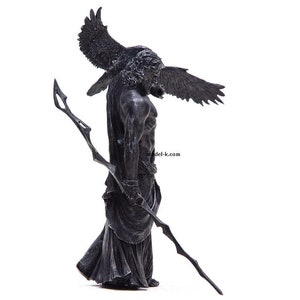 May include: A black and gray statue of a winged figure holding a spear. The figure is wearing a long robe and has a fierce expression on its face.
