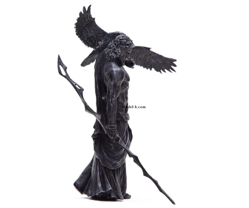 May include: A black and gray statue of a winged figure holding a spear. The figure is wearing a long robe and has a fierce expression on its face.