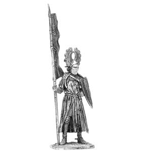 May include: A silver metal figurine of a knight in armour holding a flag and a shield. The knight is wearing a helmet with a crown and a chainmail tunic. The flag is red and white and has a design on it. The shield is round and has a design on it.