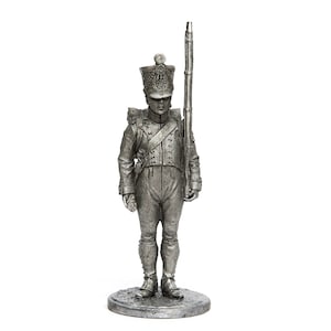 Może przedstawiać: Ołowiana figurka żołnierza w mundurze wojskowym, trzymającego karabin i stojącego na podstawie.