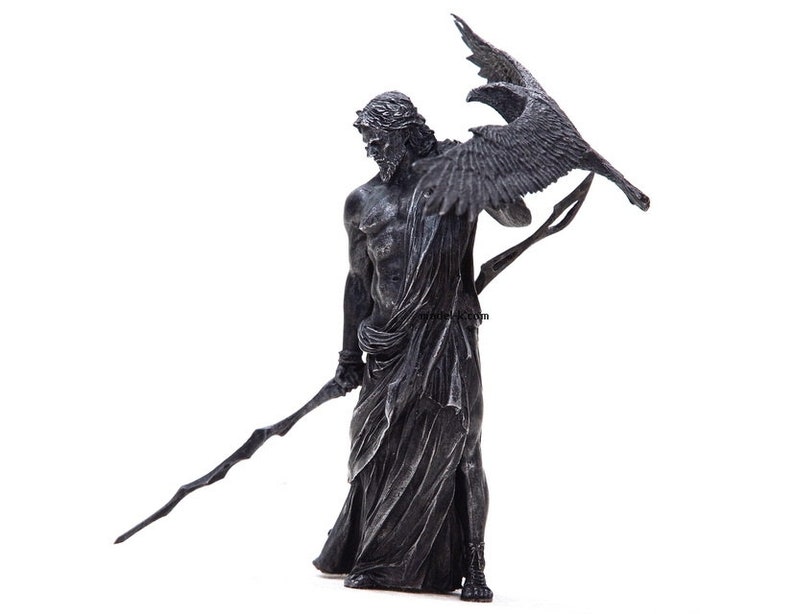 May include: A black and silver statue of a figure holding a spear and a raven. The figure is wearing a flowing robe and has a stern expression.