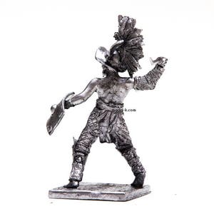 K&ouml;nnte beinhalten: Eine silberne Metallfigur eines Gladiators, der ein Schwert und einen Schild h&auml;lt. Der Gladiator tr&auml;gt einen Helm und eine R&uuml;stung. Die Figur steht auf einem kleinen Sockel.