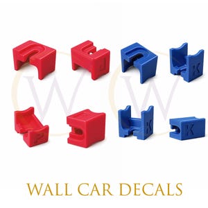 May include: A collection of eight small, three-dimensional plastic blocks in red and blue. Some blocks feature embossed letters including P, J, F, and K. The blocks have curved cutouts and varied geometric shapes. The text WALL CAR DECALS appears below.