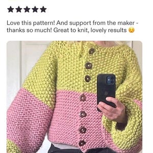 May include: A chunky knit cardigan featuring a color-blocked design with a lime green upper section and a pink lower section. The garment has long, voluminous sleeves, a round neckline, and a front button closure with six dark brown buttons.