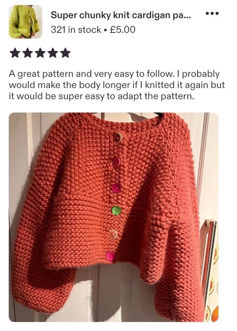 May include: A chunky knit cardigan in a solid coral color featuring a round neckline and long sleeves. The front closure is secured with five buttons in assorted colors, including light brown, pink, bright pink, green, and orange, arranged vertically.