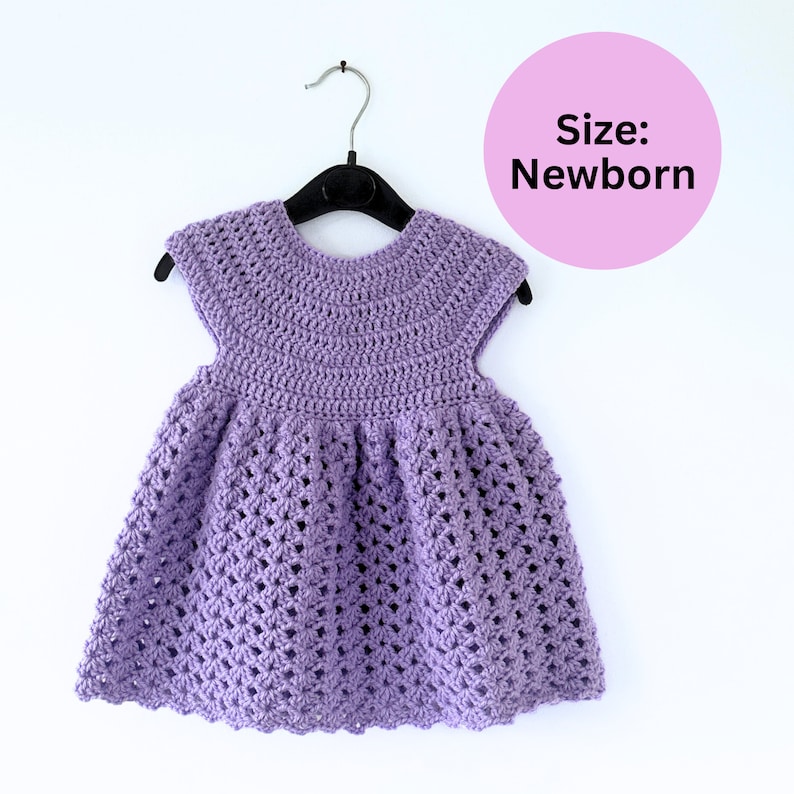 May include: A purple crocheted baby dress with a scalloped hem, hanging on a black hanger. Size: Newborn.