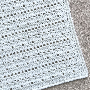 以下が含まれることがあります： ダイヤモンド模様の白い編み物の正方形