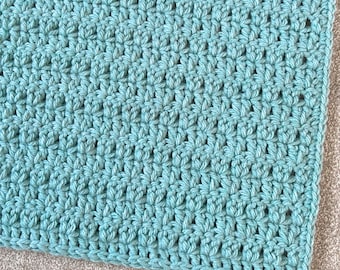 May include: A close-up of a teal crocheted fabric with a textured, woven pattern.